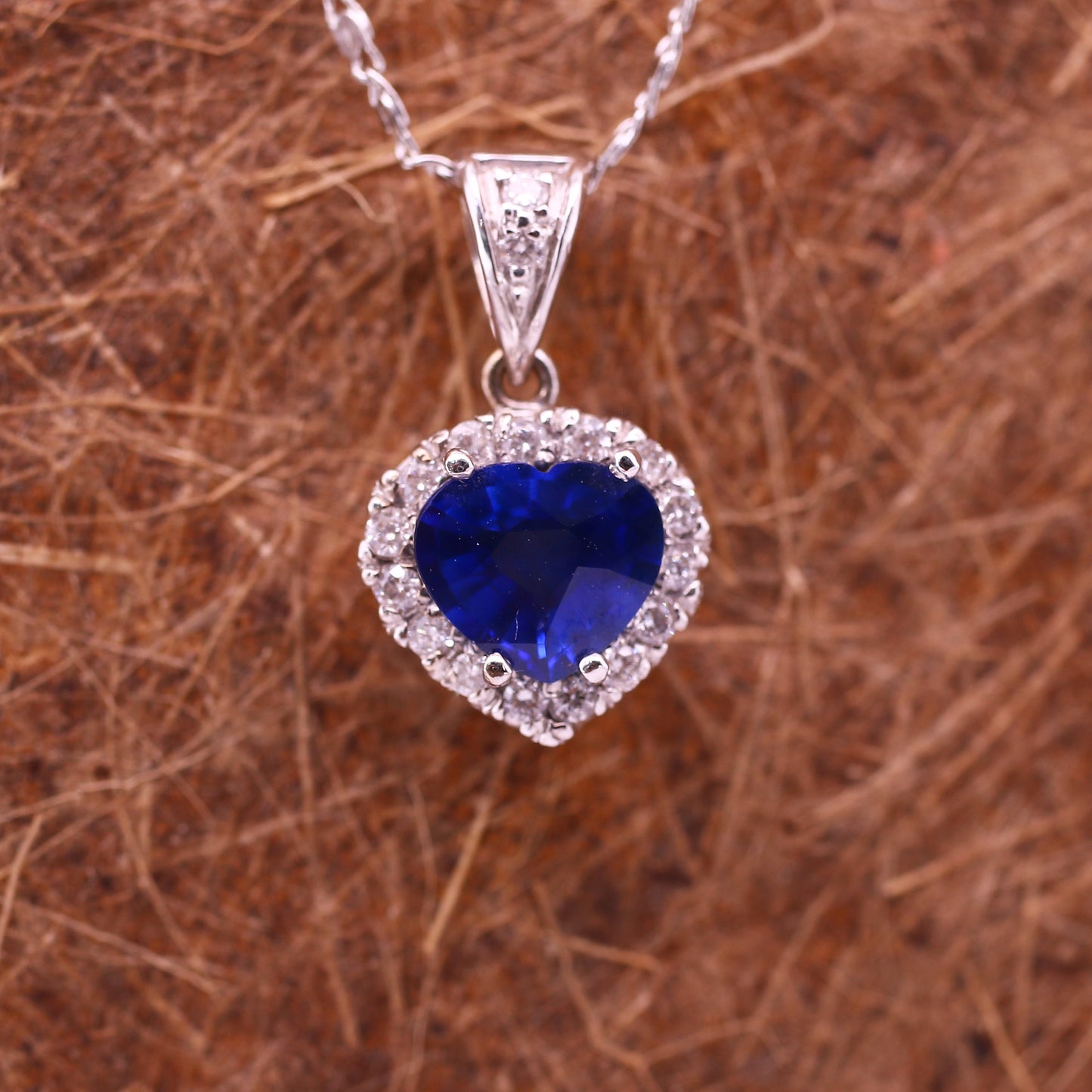 A unique 18K White Gold Pendant with a excellent natural Heart cut Blue Sapphire in the Center. A Heart design Diamond halo enhances the vivid blue of the Precious Stone.
