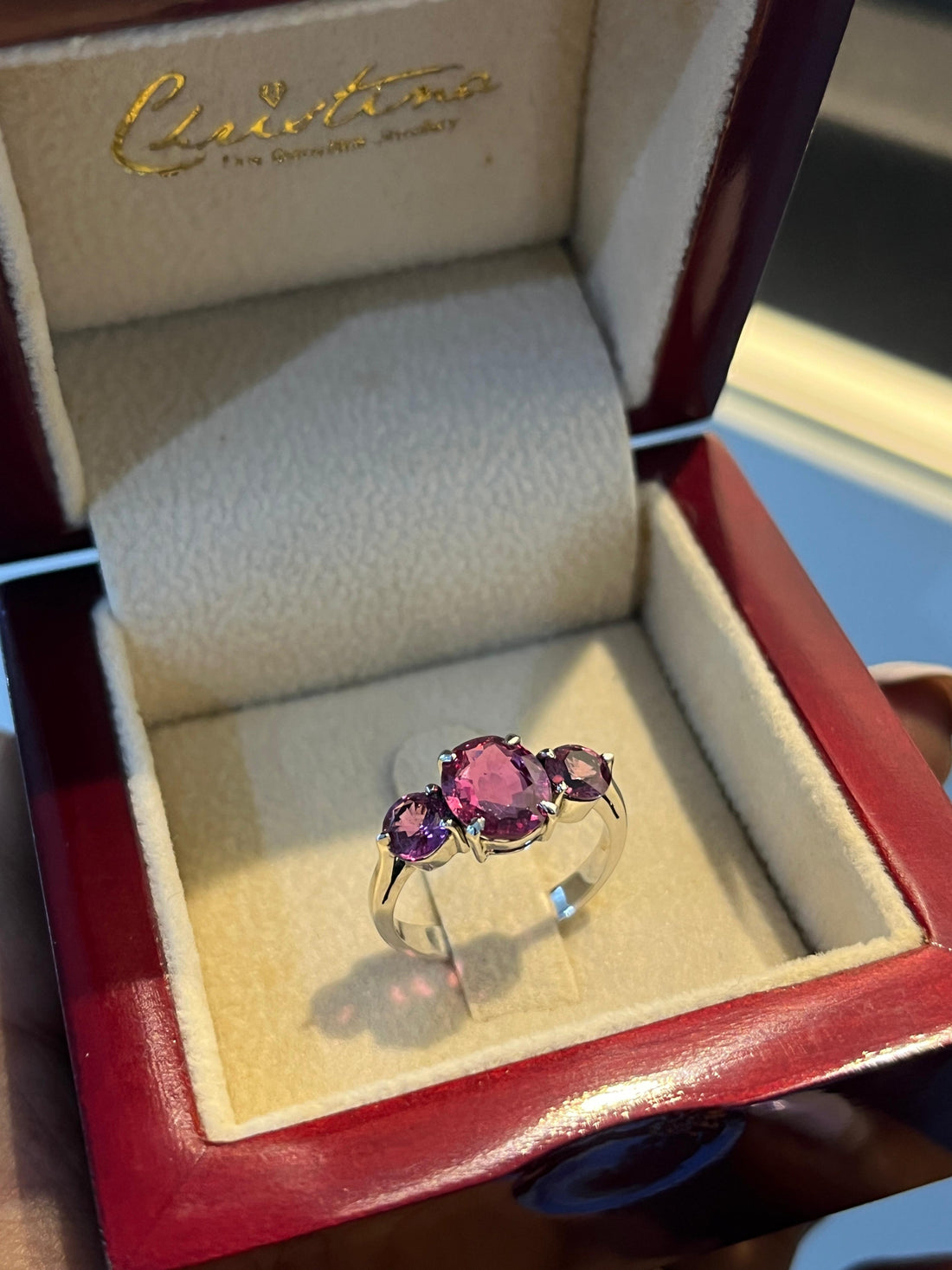 A ring set with purple stones, presented in a Christina Jewellers box