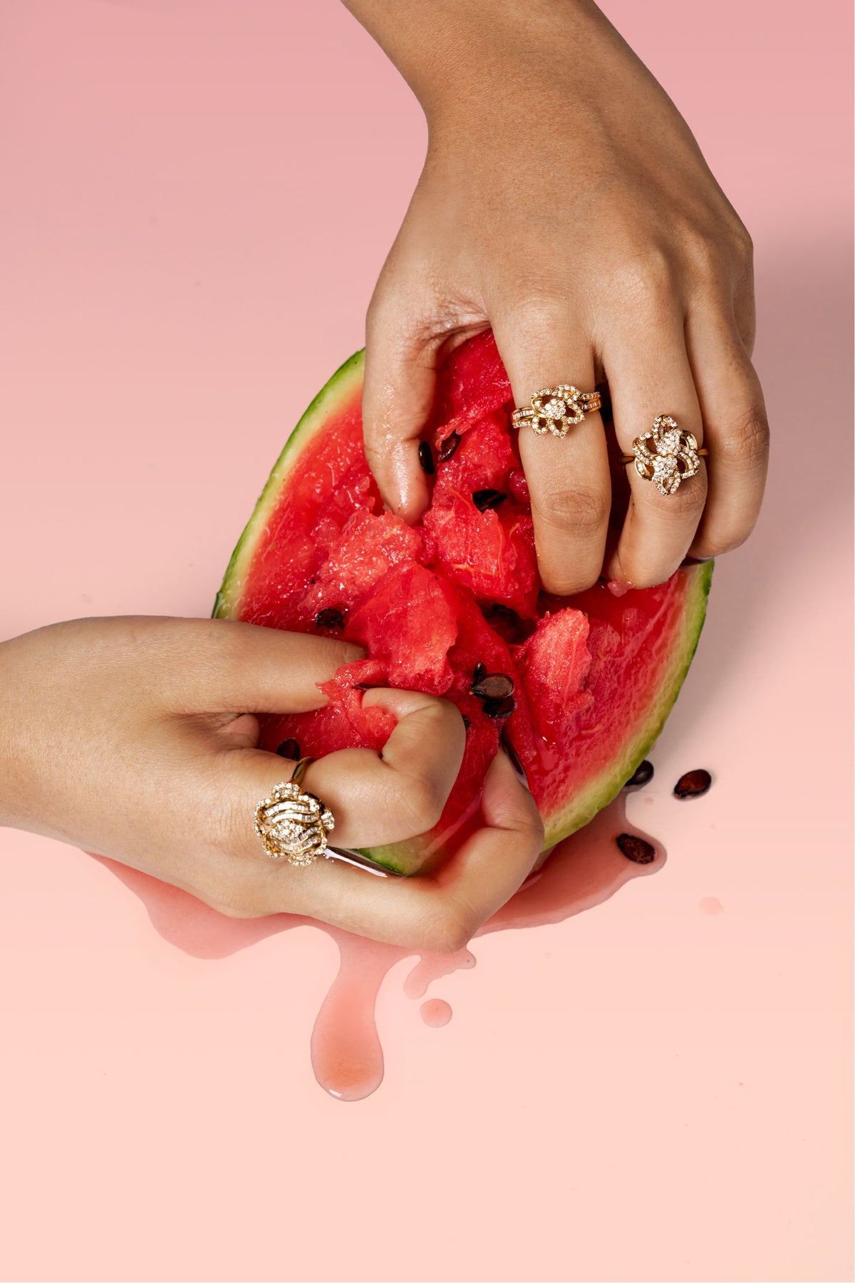 Hands wearing rings pulling apart a watermelon