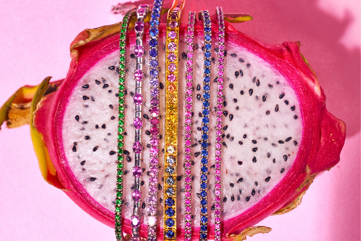 Multicoloured gemstone bangles laid across a dragon fruit