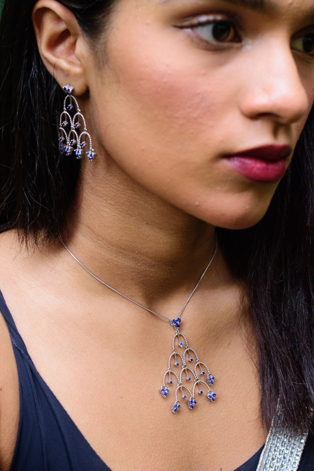 Woman wearing drop earrings and a matching pendant necklace