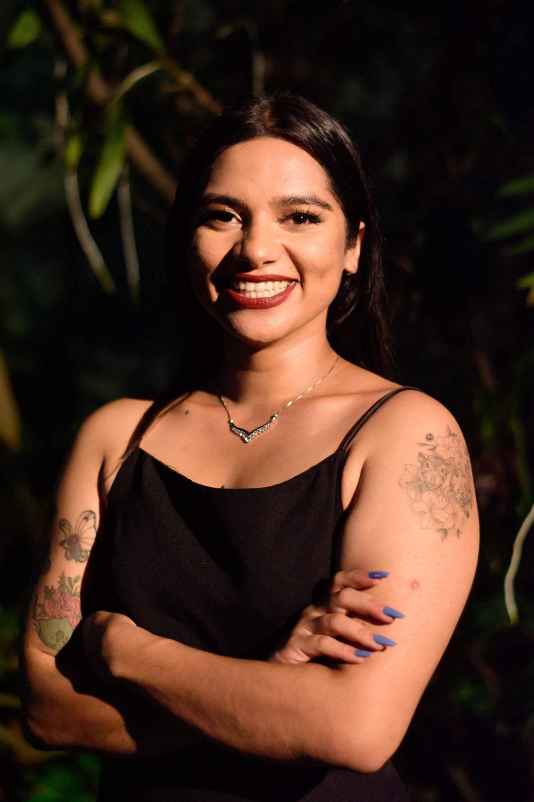 Smiling woman in a black top against green leaves