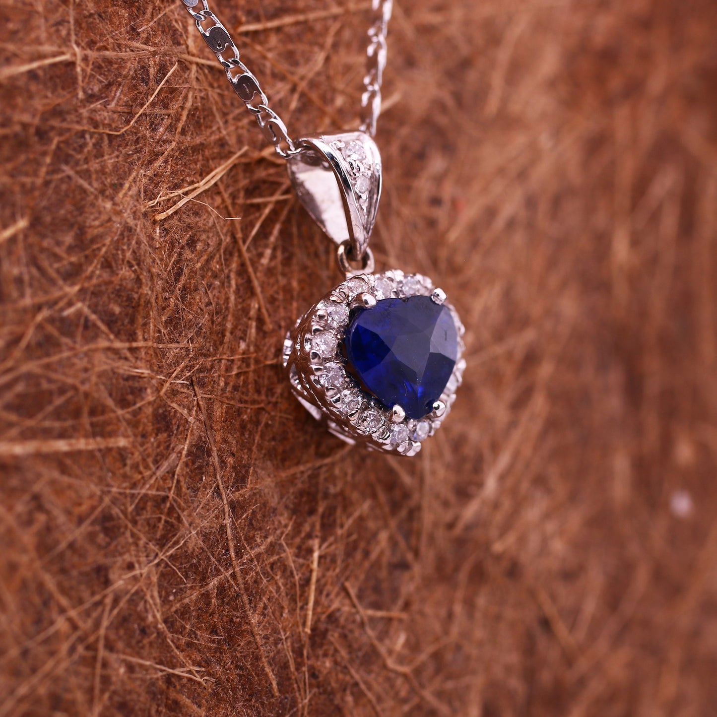 A unique 18K White Gold Pendant with a excellent natural Heart cut Blue Sapphire in the Center. A Heart design Diamond halo enhances the vivid blue of the Precious Stone.
